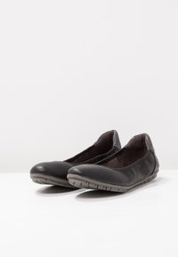 Black leather ballet flats with a flexible gray rubber sole, rounded toe, and textured heel accent. Suede-like interior lining.