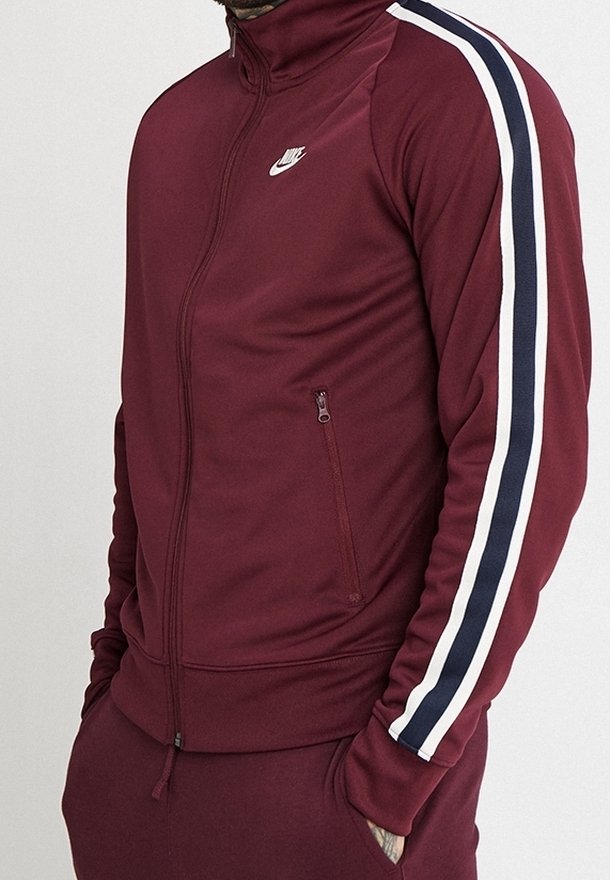 Bordowa rozpinana bluza dresowa z białymi i granatowymi paskami na rękawach. Posiada wysoki kołnierz i zamykaną na zamek kieszeń boczną. Logo Nike na piersi.