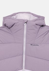 Veste rembourrée violet clair avec capuche, dotée d'une fermeture éclair sur le devant et de coutures diagonales. Comprend un logo Columbia sur la poitrine et une texture lisse.
