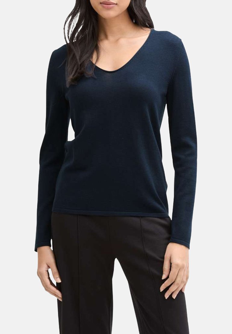 Haut bleu marine à manches longues et col en V, fabriqué en tissu doux avec un design ajusté, associé à un pantalon noir, présentant une texture lisse.