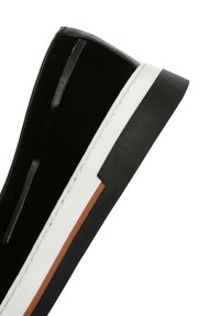 Black suede slip-on sneaker with white rubber sole, black textured heel cap, and brown accent stripe. Features minimal stitching and ventilation details.