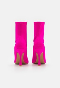 Klare pink ankelstøvler med en tætsiddende design, glat tekstur, stiletto-hæle og diskrete syninger ved sømmene.