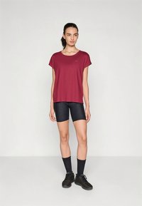 Tumepruun lühikeste varrukatega top ümmarguse kaelusega, mida on kombineeritud mustade rattapükstega. Tekstureeritud materjal ja stiilsed mustad jalatsid täiendavad välimust.