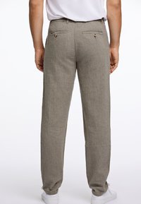 Pantalons en lin à motifs gris clair avec deux poches à l'arrière. Caractérisés par une coupe décontractée et un design à jambe fuselée, associés à des baskets blanches.