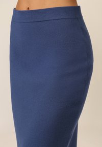 Gonna blu di lunghezza al ginocchio realizzata in un tessuto morbido e testurizzato, con una vita senza cuciture. Il design è aderente, con una superficie liscia.