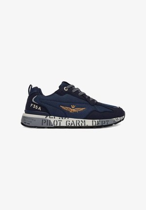 Sneaker blu navy con lacci neri e bianchi, emblema dorato alato sul lato, suola grigia con scritte e segni neri in stile militare.