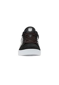 Zapatillas de ante negras con suelas de goma blancas, adornadas con cordones marrones, tres rayas blancas a los lados y un logo en la lengüeta.