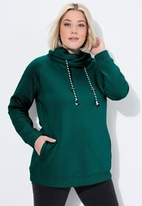 Felpa verde con cappuccio, collo a barchetta, cordini, tasche frontali e polsini a costine. Texture morbida, vestibilità casual e maniche lunghe.