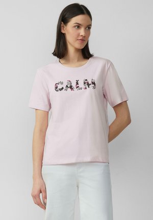 T-shirt en coton rose à manches courtes, arborant le mot "CALM" dans un motif noir et floral sur le devant.