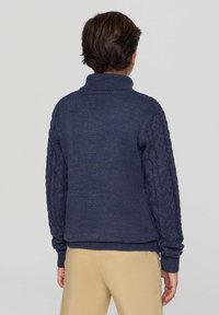 Granatowy sweter z dzianiny z wysokim kołnierzem, teksturowanymi rękawami w splot kablowy oraz ściągaczami u mankietów i na dole. Gładka faktura ciała, luźny krój.