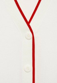 Cardigan bianco con un colletto a coste rosso, caratterizzato da tre bottoni bianchi sul davanti. Il tessuto appare morbido e strutturato.