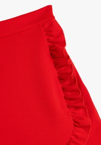 Rote Rock aus einem glatten, strukturierten Stoff. Verfügt über ein Rüschendetail an der Seitennaht entlang des Saums, das die gesamte Form und das Design verbessert.