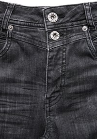 Czarne dżinsy o wysokim stanie z dwoma błyszczącymi srebrnymi zapięciami i subtelnym, wyblakłym teksturą na tkaninie.