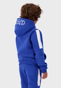 Blue hoodie with white side stripes, featuring a kangaroo pocket and logo on the hood. Material appears soft and textured.