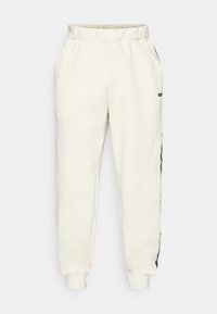 Cremefarvede sweatpants med elastisk talje, tætsiddende manchetter og sorte sideaccenter. Fremstillet af et blødt, tekstureret stof.