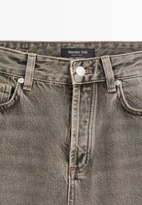 Jeans in denim grigio con un design classico a cinque tasche, chiusura a bottoni e dettagli cuciti. Presenta un'etichetta Massimo Dutti alla vita.