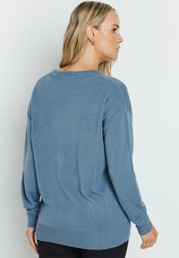 Blauer Strickpullover mit lässiger Passform, überschnittenen Schultern und gerippten Bündchen und Saum. Weicher Stoff und lässiges Design, das sich gut zum Schichten eignet.