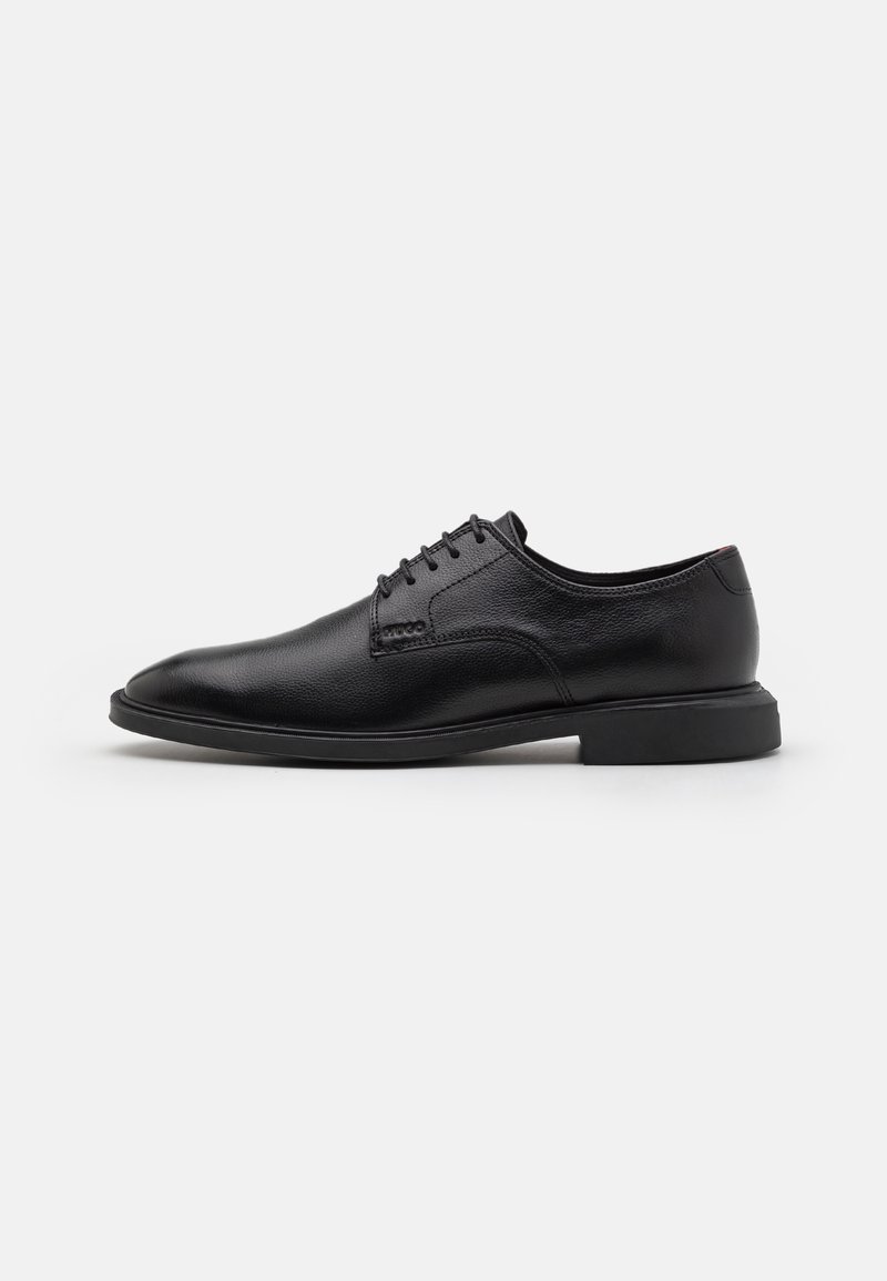 Chaussure habillée en cuir noir à finition lisse, bout arrondi et design à lacets. Elle présente un talon bas et des accents de coutures subtiles.