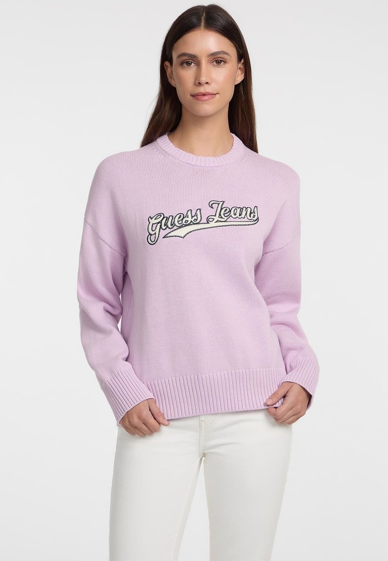 Hellblauer Strickpullover mit gerippten Bündchen und Saum, mit aufgesticktem "Guess Jeans" in dunklem Faden über der Brust.