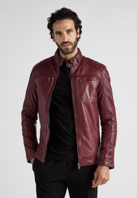 Burgunderfarbene Lederjacke mit Reißverschlusstaschen, hohem Kragen und gesteppten Details an Schultern und Ärmeln. Glatte Textur mit taillierter Passform.