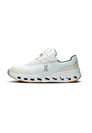 Weißer Sportschuh mit grauem Logo, hellbeigen Akzenten und einer einzigartigen Sohle mit schwarzen Belüftungsschlitzen sowie einer Gummilaufsohle.