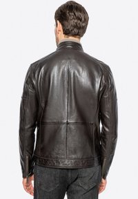 Giacca in pelle marrone con una texture liscia, caratterizzata da cuciture verticali, polsini con zip e colletto alla coreana, mostrata da dietro.