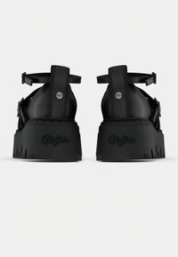 Para czarnych sandałów na platformie z paskami wokół kostki i wytłoczonym logo "Buffalo" na grubych podeszwach, widocznych od tyłu.