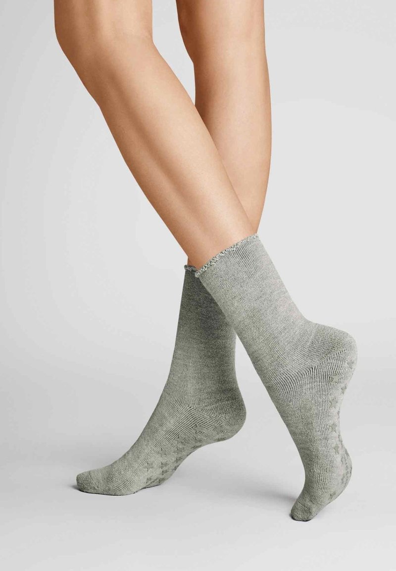 Grüne Stricksocken mit einer weichen Textur, geripptem Design und ausgefranstem Bündchen, die einen lässigen, komfortablen Stil zeigen.