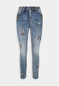 Modré džíny skinny z denimové látky s různými výšivkami květin a ovoce, s mírným blednutím a děravými záplatami na nohavicích.