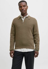 Pruun kudumissviiter, millel on tõmbluku krae, kantud heledate triipudega särke. Omab pikki varrukaid ja lõdva lõikega.