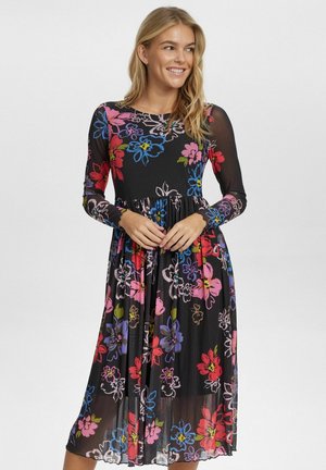 Blommig klänning med långa ärmar, svart bakgrund och färgglada blommönster i rosa, blått och grönt; åtsittande midja med en flödande kjol.