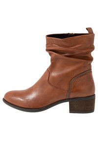 Braune Leder-Stiefelette mit schlaffem Schaft, seitlichem Reißverschluss, niedrigem Blockabsatz und abgerundeter Zehenpartie auf weißem Hintergrund.