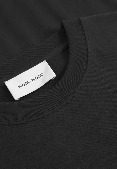Tricou negru din bumbac, cu guler ribflat și o etichetă albă pe care scrie "WOOD WOOD". Textură netedă și design simplu.