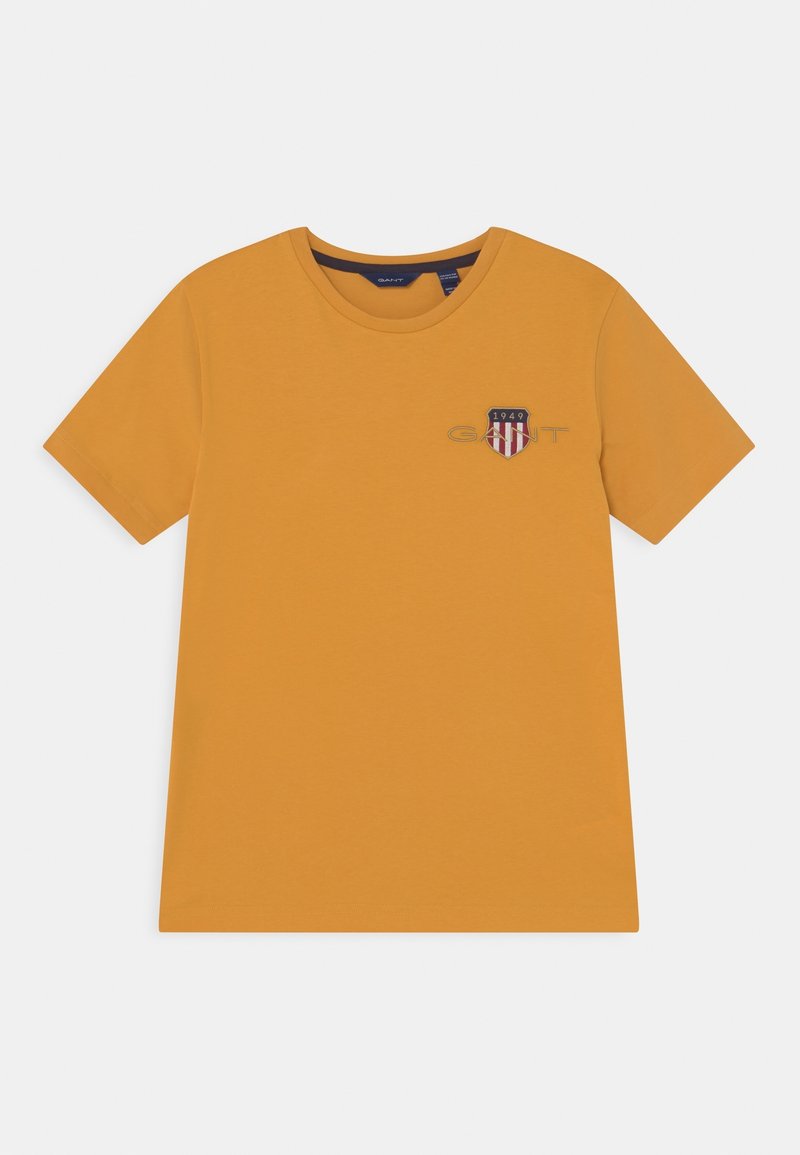 Musztardowa żółta koszulka z krótkim rękawem wykonana z bawełny, z małym haftowanym logo w kształcie tarczy na lewej piersi.