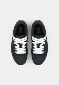 Sorte sneakers med hvite lisser, teksturert overmateriale og en glatt gummisal. Innvendig har de røde "Flight"-bokstaver.