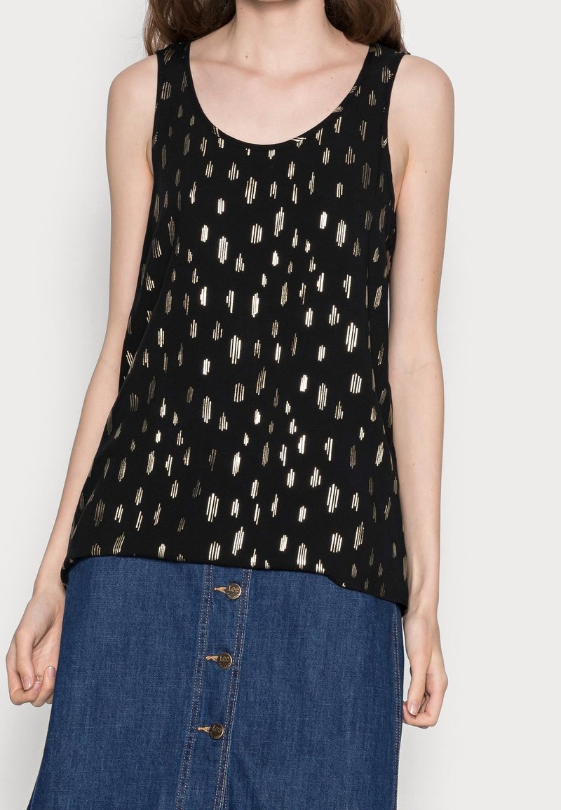 Débardeur noir avec des rayures métalliques dorées verticales et diagonales, doté d'un col en U et sans manches, associé à une jupe en denim.