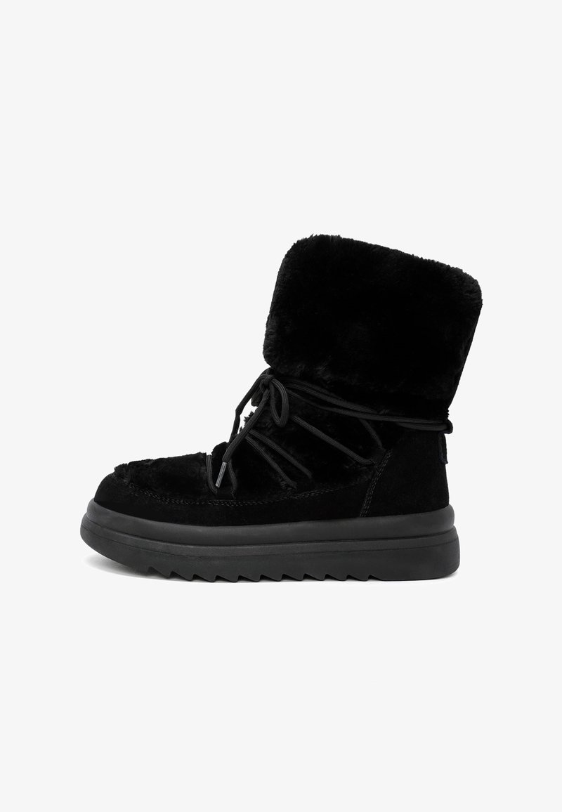 Botín negro hasta el tobillo con forro de piel sintética, suela de goma y cordones de tela. Presenta un cuello alto y esponjoso y un exterior texturizado.