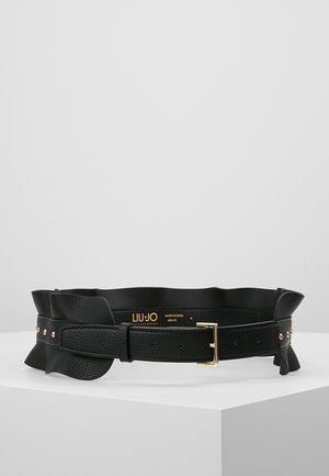 Ceinture en cuir noir texturé avec des clous dorés et une boucle rectangulaire dorée, présentée sur un piédestal blanc sur fond gris.