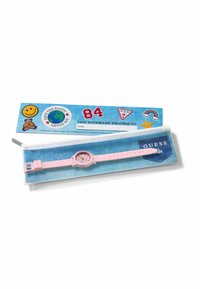 Montre rose pour enfants sur une pochette zippée en jean bleu avec le logo Guess Kids, à côté d'un marque-page coloré avec des autocollants de la Terre, d'un smiley et d'un arc-en-ciel.