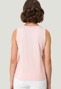 Top sin mangas de color rosa claro con escote redondo y textura suave, presentando un dobladillo ligeramente curvado y sin herrajes visibles.