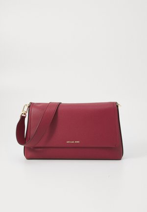Czerwona skórzana torba na ramię z pozłacanym zapięciem i regulowanym paskiem, z małym logo "Michael Kors" na przedniej klapie.