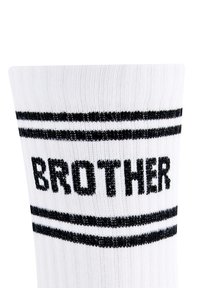 Weißer Socken mit dem Wort "BRUDER" in Schwarz, mit zwei horizontalen schwarzen Streifen oben. Strukturiertes Strickmaterial.