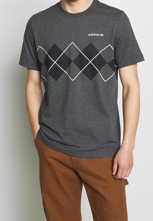 Miesten harmaa lyhythihainen t-paita, jossa on tummansininen ja kerma-valkoinen timanttikuvio, sekä Adidas-logo rinnassa. Pehmeää puuvillamateriaalia.