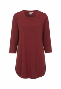 Bordo tunik, dengan lengan tiga perempat, terbuat dari kain lembut dengan hem melengkung dan aksen samping yang menampilkan tombol untuk detail.