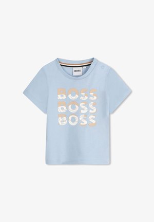 T-shirt azzurro chiaro a maniche corte con la scritta "BOSS" stampata in un testo beige stilizzato. Presenta un collo a giro e bottoni decorativi sulla spalla.