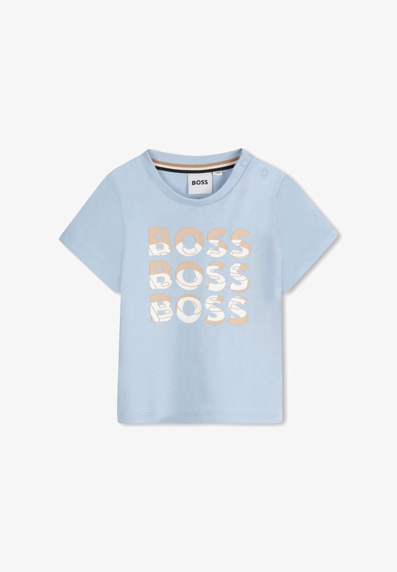 T-shirt bleu clair à manches courtes avec "BOSS" imprimé en texte beige stylisé. Présente un col rond et des pressions décoratives sur l'épaule.