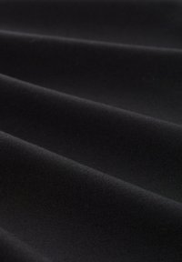 Schwarzer Stoff mit einer glatten, matten Textur, der sanfte Falten und einen leichten Glanz zeigt und das flexible, leichte Material betont.