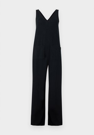 Tuta nera senza maniche con scollo a V e tasche applicate frontali, caratterizzata da pantaloni a gamba larga su uno sfondo grigio chiaro.