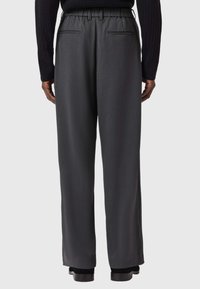 Gray, wide-leg trousers with a smooth texture, featuring an elastic waistband and two back pockets, displayed from a rear view.