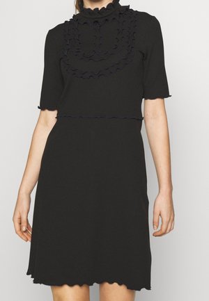 Robe noire à manches courtes avec col montant froufrouté et détail à volants superposés sur la poitrine, bords festonnés aux manches et à l'ourlet.